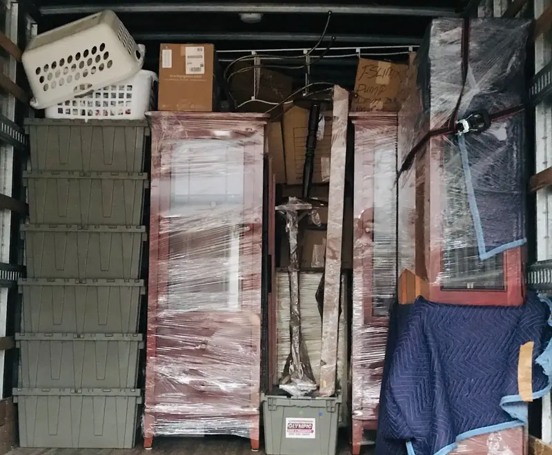 Neatly stacked boxes and padded, wrapped furniture inside a moving truck