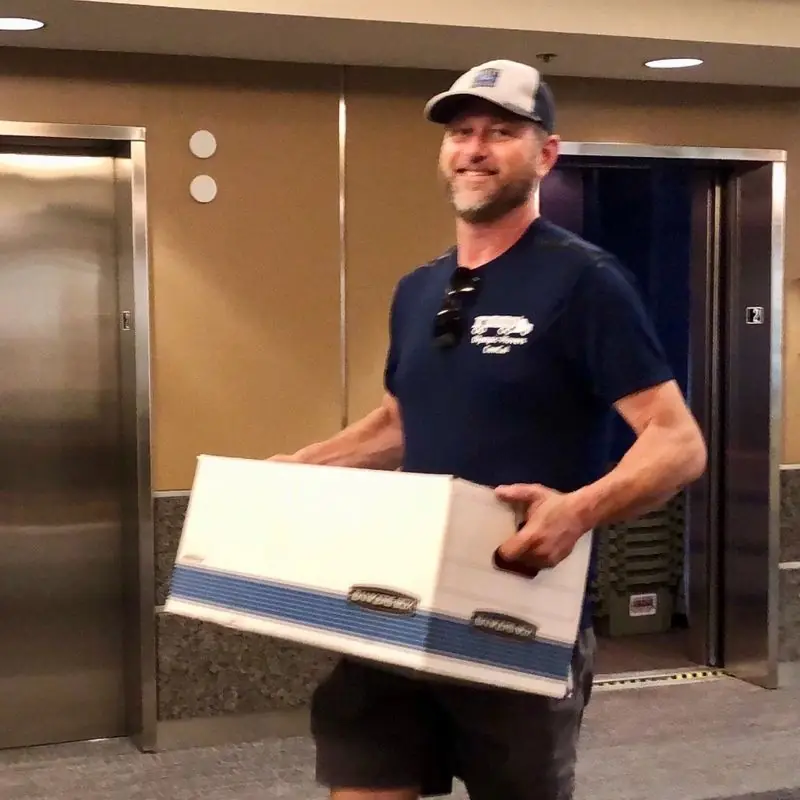 Olympic mover carrying a box down a hallway